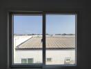 View from a window showing rooftops and a clear sky