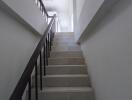 Interior staircase with white walls and steps leading up to another floor