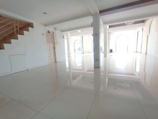Spacious, brightly lit living area with tile flooring and staircase