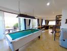 Spacious open-plan living area with pool table and balcony access