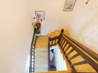 Bright staircase with wooden bannisters and tiled floors