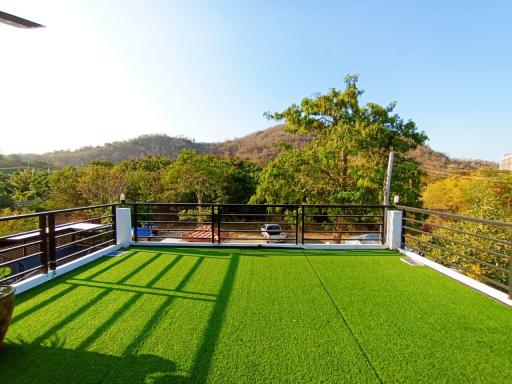 Spacious balcony with artificial grass and panoramic view of hills and greenery
