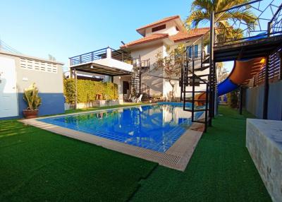 Spacious outdoor area with swimming pool, artificial grass, and residential building