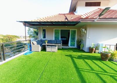 Spacious balcony with artificial grass and outdoor furniture