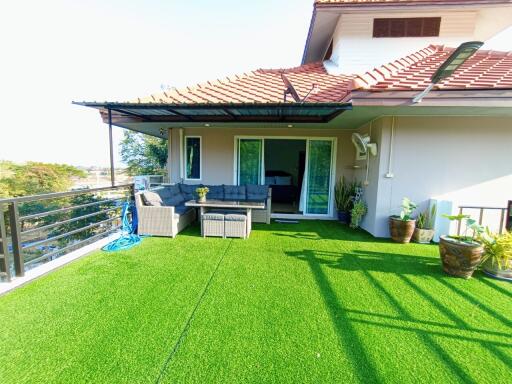 Spacious balcony with artificial grass and outdoor furniture