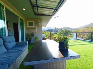 Spacious balcony with comfortable seating, artificial grass, and scenic view