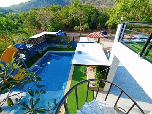 Spacious outdoor area with swimming pool, artificial turf, and balcony with a view of nature