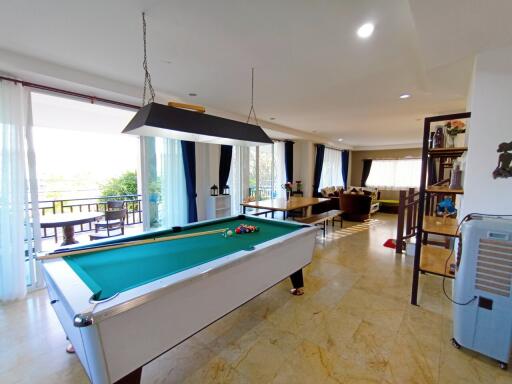 Spacious living room with pool table, balcony access, and ample natural light