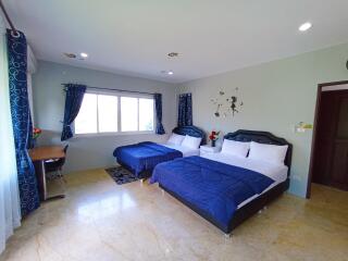 Spacious bedroom with two beds, large windows, and tiled flooring