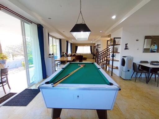 Spacious living area with a pool table, large windows, and tiled flooring