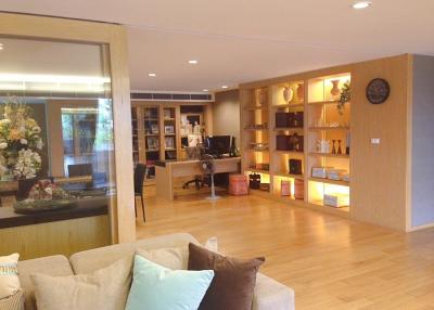 Spacious living room with wooden flooring, bookshelves, and ample lighting
