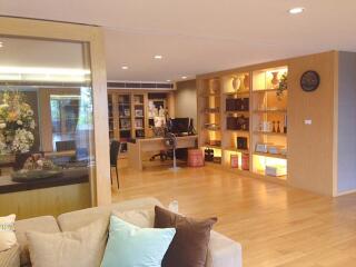 Spacious living room with wooden flooring, bookshelves, and ample lighting