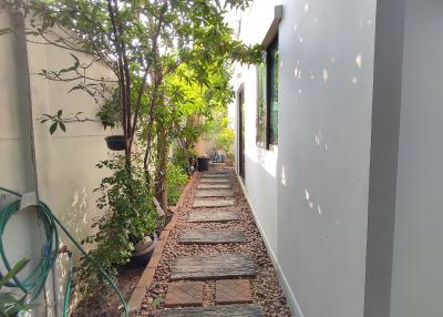 Peaceful garden path by the side of a building with natural stone tiles and lush greenery