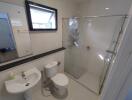 Modern white bathroom with glass shower and natural light