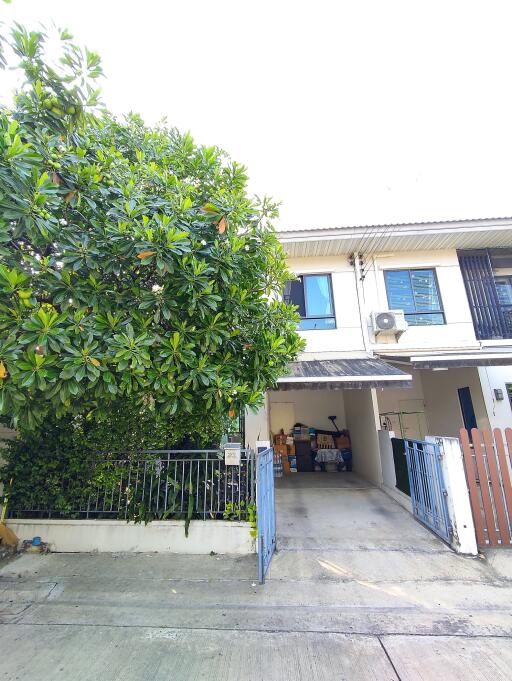 Front view of a two-story house with a driveway and a large tree