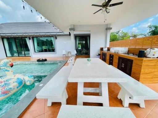 Spacious outdoor patio area with poolside dining table and kitchenette