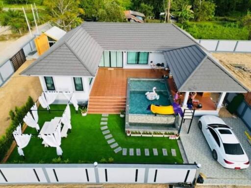 Aerial view of a residential property with a pool, garden, and outdoor dining area