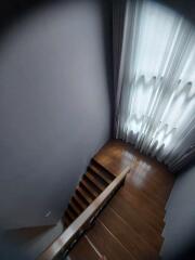 Dimly lit staircase with wooden steps and white curtains