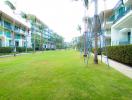 Lush green lawn in a residential community with modern apartments and amenities