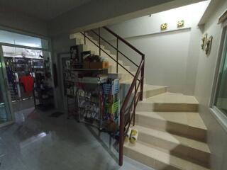 Spacious staircase area with storage shelving and tile flooring
