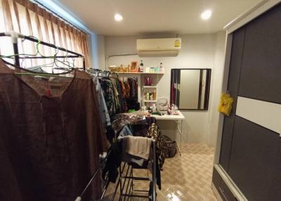 Cluttered bedroom with clothes rack and large wardrobe