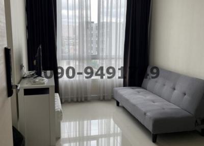 Modern living room with city view through large window, furnished with a gray sofa and glossy floor