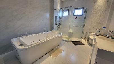 Spacious modern bathroom with bathtub and glass shower enclosure