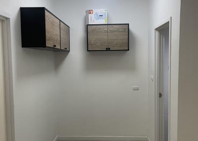Compact hallway with mounted storage cabinets and white tiled flooring