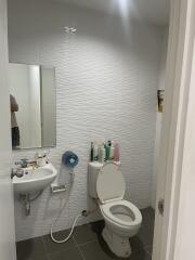 Compact bathroom with white wall tiles, toilet, and pedestal sink