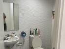 Compact bathroom with white wall tiles, toilet, and pedestal sink