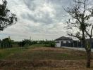 Suburban home exterior with open land under a cloudy sky