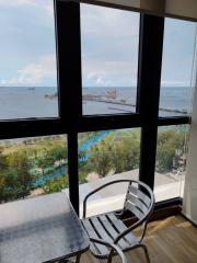 Room with large windows overlooking the sea, with a chair and table