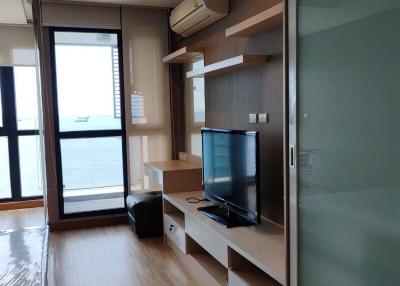 Modern living room with a view of the sea, featuring wooden flooring and a wall-mounted TV setup