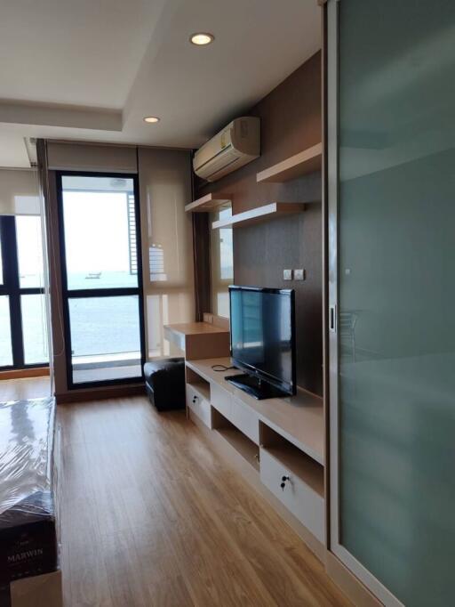 Modern living room with a view of the sea, featuring wooden flooring and a wall-mounted TV setup