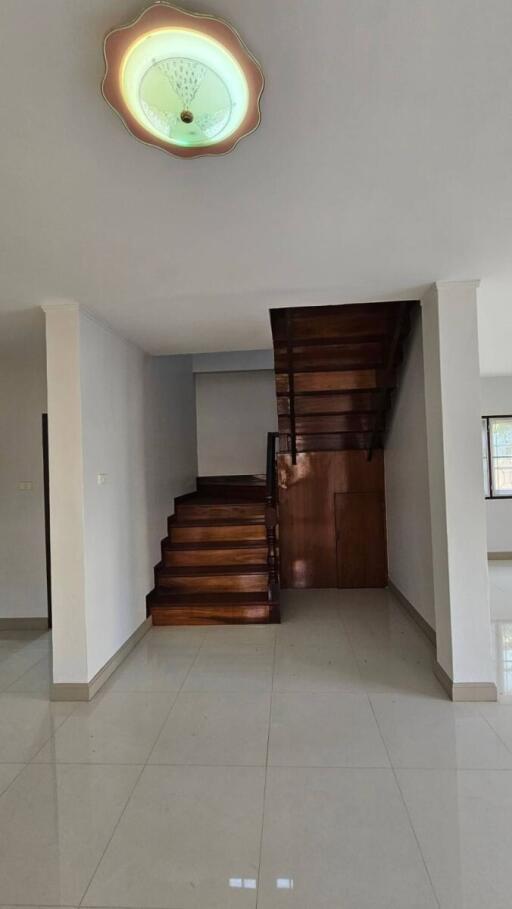 Spacious hallway with wooden staircase and tiled flooring