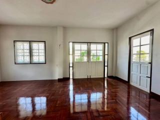 Spacious bedroom with polished wooden floors and ample natural light