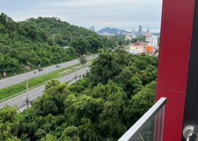 View from a high-rise apartment balcony overlooking greenery and a cityscape