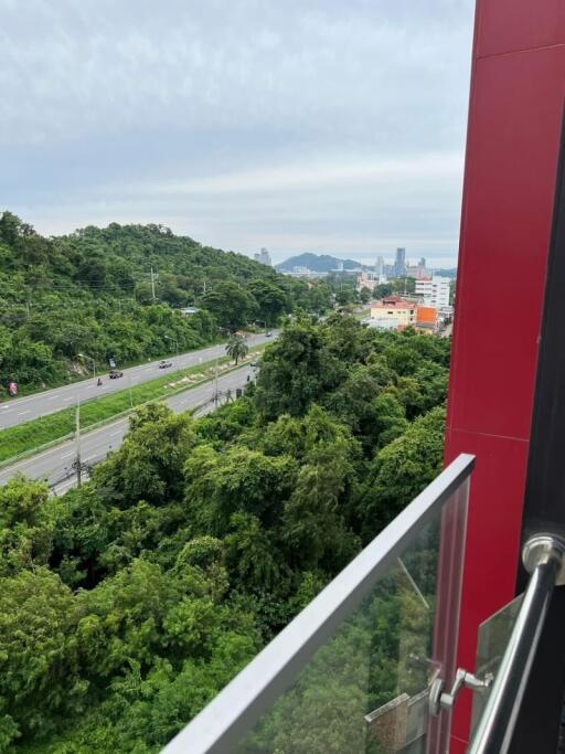 View from a high-rise apartment balcony overlooking greenery and a cityscape