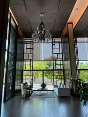 Modern lobby area with high ceiling, large windows, and stylish seating