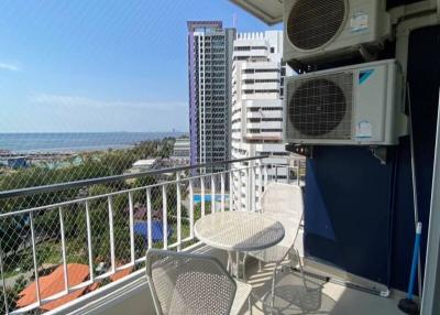 Balcony with outdoor seating and a view of high-rise buildings with the ocean in the background