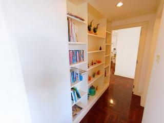 Brightly lit hallway with bookshelves and hardwood flooring