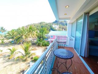 Spacious balcony with ocean view, overlooking surrounding greenery and nearby structures