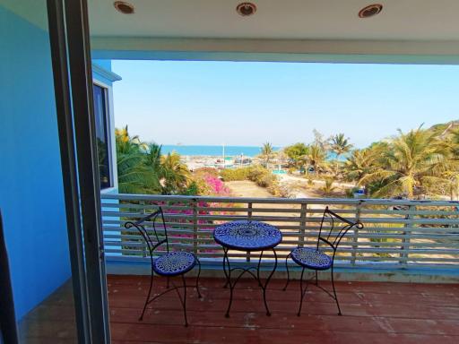 Spacious balcony with ocean view, seating arrangement and tropical surroundings