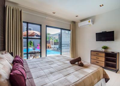 Modern bedroom with pool view, king-sized bed, and mounted television