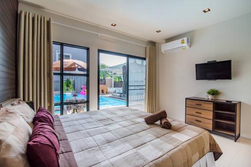 Modern bedroom with pool view, king-sized bed, and mounted television