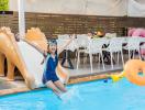 Child enjoying the swimming pool with slide in a residential backyard
