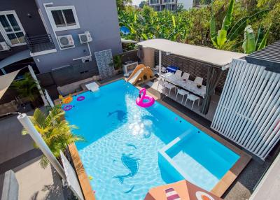 Private swimming pool with inflatable toys and patio area in a sunny backyard