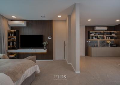Modern bedroom with combined living space featuring a wall-mounted TV and integrated shelving units