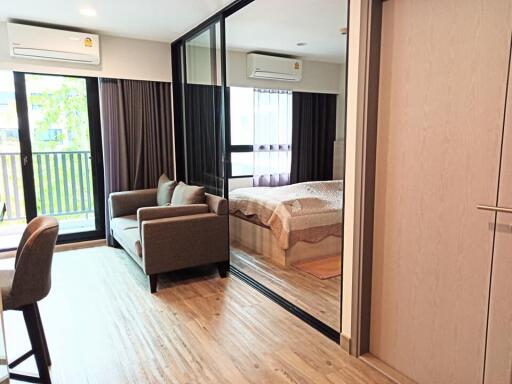 Modern bedroom with adjoining living area featuring large windows and natural light