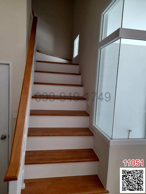 Modern wooden staircase with white walls and large window